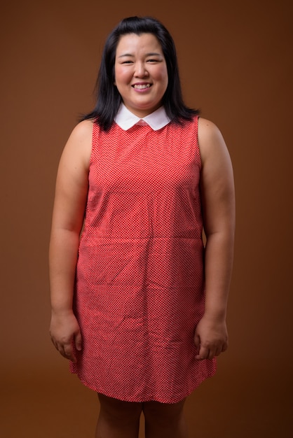 schöne übergewichtige asiatische Frau, die rotes Kleid trägt