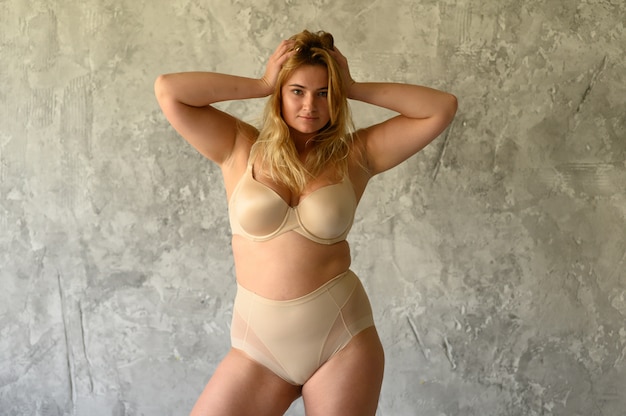 Foto schöne übergewichtige frau im beige badeanzug auf grauem hintergrund