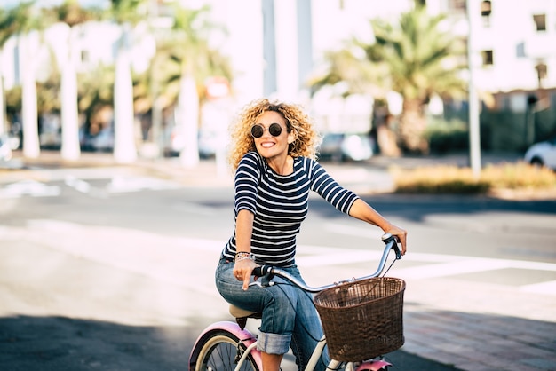 Schöne und fröhliche erwachsene junge frau genießen eine radtour in der sonnigen städtischen outdoor-freizeitaktivität in der stadt