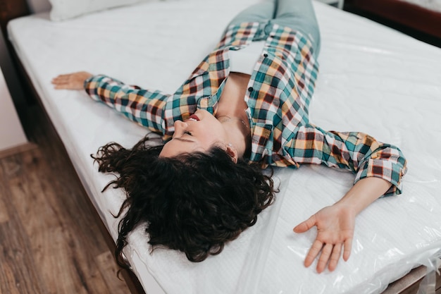 Foto schöne und glückliche frau mittleren alters, die sich in einem großen möbelhaus für ein neues bett und eine matratze entscheidet