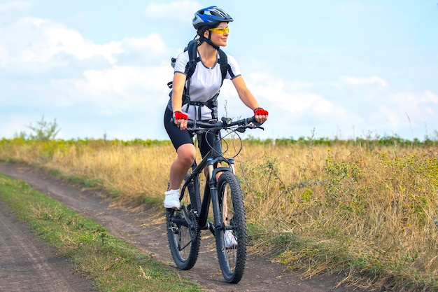 Schöne und glückliche Radfahrerin fährt Fahrrad auf der Straße in der Natur. Gesunder Lebensstil und Sport. Freizeit und Hobbys