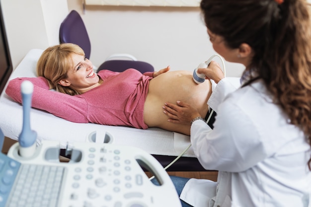 Schöne und glückliche werdende Mutter macht Ultraschalluntersuchung in der Pränatalklinik.
