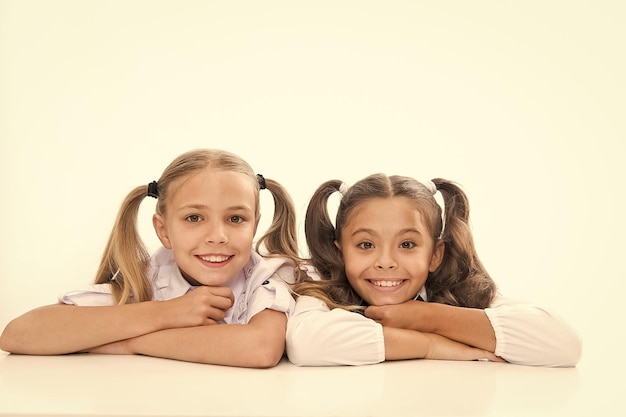 Schöne und intelligente Schulmädchen in Zöpfen Niedliche kleine Mädchen lächelnd isoliert auf weiß Glückliche kleine Mädchen in der Schule Adorable Baby Girls in der Klasse