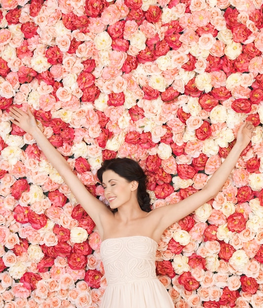 schöne und junge Frau mit Hintergrund voller Rosen