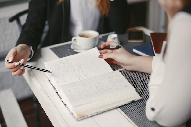 schöne und stilvolle junge Geschäftsfrauen, die in einem Café und in einem Arbeiten sitzen