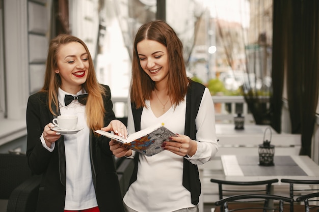 schöne und stilvolle junge Geschäftsfrauen, die in einem Café und in einem Arbeiten stehen