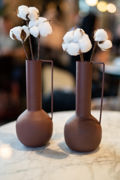 Schöne Vase mit Baumwollblumen auf dem Tisch