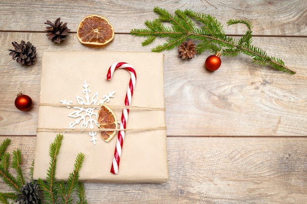 Schöne verpackte Geschenkbox mit Tannenzweigen Zuckerstangendekor auf Holzuntergrund Weihnachten