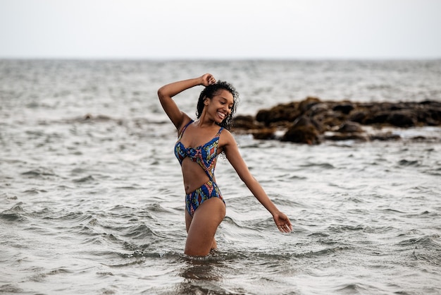 Schöne, verspielte schwarze Frau im Bikini an einem vulkanischen Strand in Santo Antao, Kap Verde