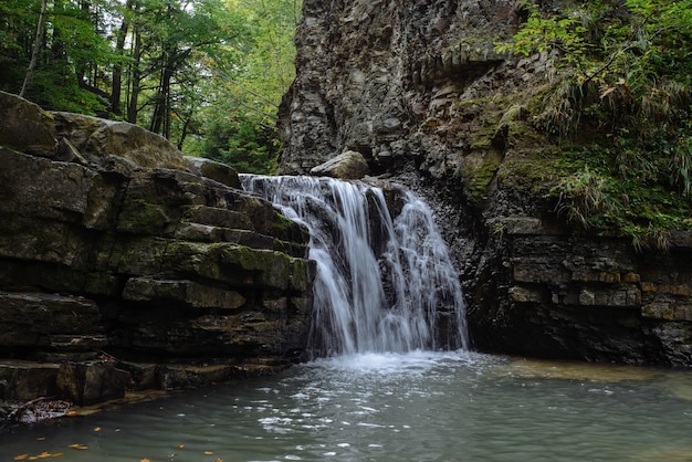 Schöne Wasserfallnahaufnahme. kleiner Waldfluss. Wasserströme fallen vom Felsen.