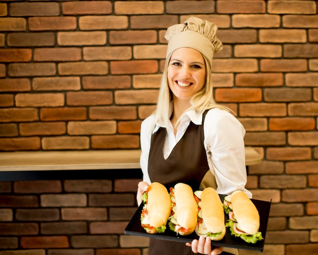 Schöne weibliche Bäckerei, die mit verschiedenen Arten von Sandwichen in der Bäckerei aufwirft