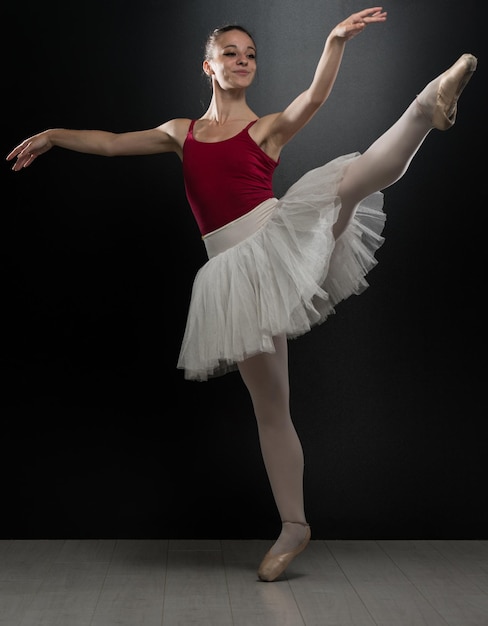 Schöne weibliche Ballett-Tänzerin auf schwarzem Hintergrund Ballerina trägt ein Ballettröckchen und Spitzenschuhe