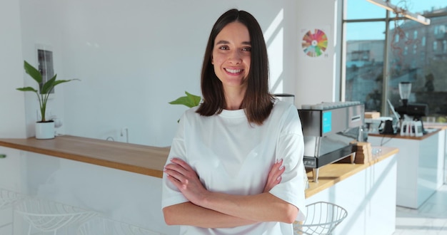 Schöne weibliche Barista ist glückliches Lächeln in der Café-Bar Porträt eines glücklichen Mitarbeiters hinter einer gemütlichen Café-Theke im Restaurant