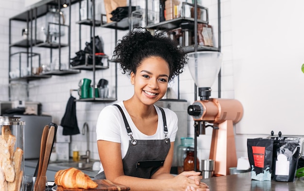 Schöne weibliche Barista schaut in die Kamera