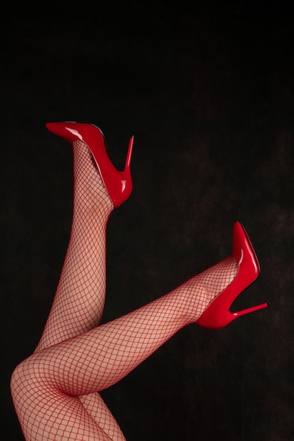 Schöne weibliche Beine in Netzstrümpfen und roten Schuhen