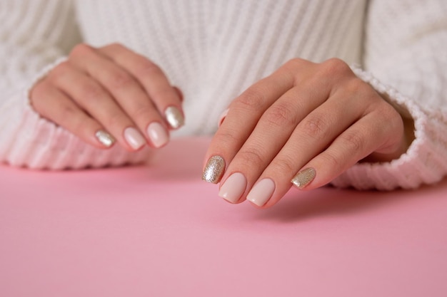 Schöne weibliche Hände mit beigefarbenen Manikürenägeln auf rosa Hintergrund