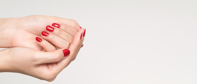 Schöne weibliche Hand, die rote Nägel aus Acrylgel malt. Modestil