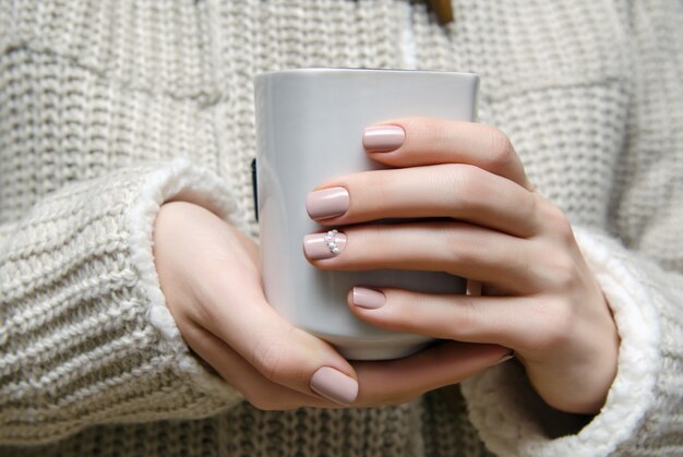 Schöne weibliche Hand mit beige Nageldesign.