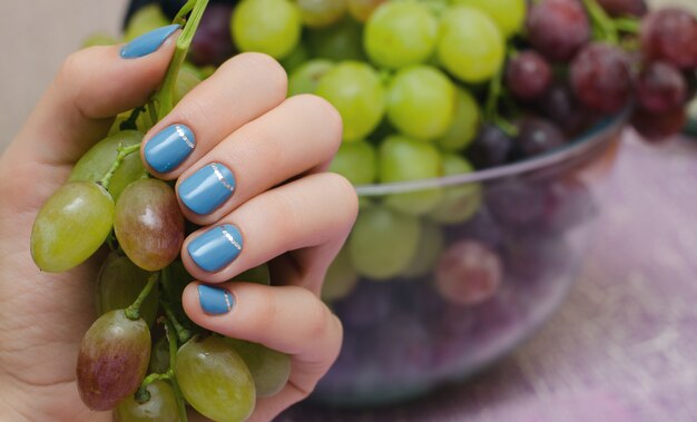 Schöne weibliche Hand mit blauem Nageldesign.