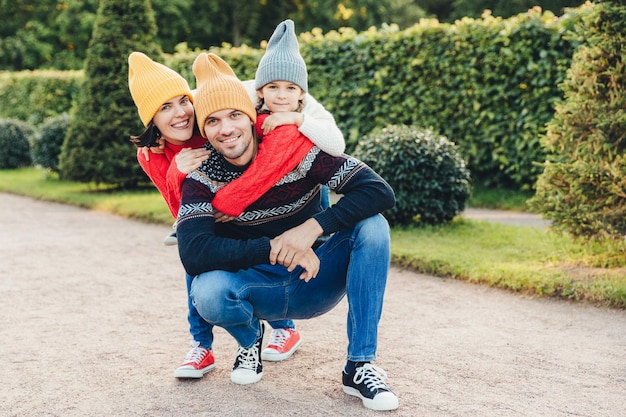 Foto schöne weibliche kleine mädchen umarmen ihren gutaussehenden vater und ehemann haben eine gute beziehung haben einen aktiven lebensstil pose gegen grüne bäume familie haben zusammen gehen umarmen sich