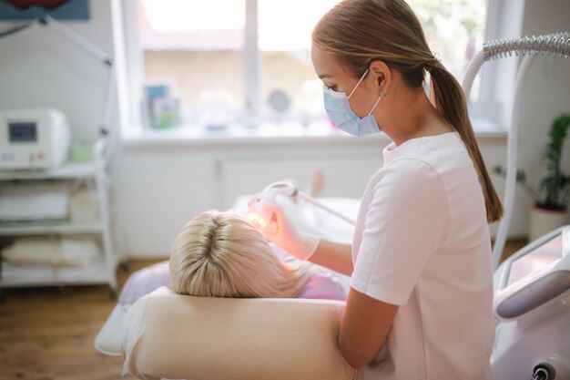 Schöne weibliche Patientin bekommt eine Gesichtshautbehandlung, während sie in der medizinischen Klinik liegt