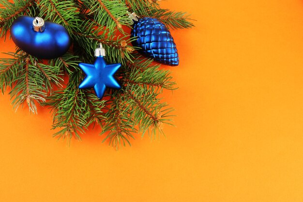 Schöne Weihnachtsdekorationen auf Tannenbaum auf orangem Hintergrund