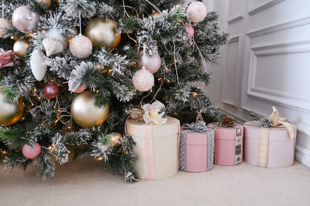 Schöne Weihnachtsgeschenkboxen auf Boden nahe Tannenbaum im Raum