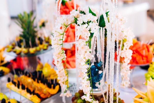 Schöne weiße Blumen in einer Vasenfrucht, die auf Hochzeitsempfang Nahaufnahme schneidet