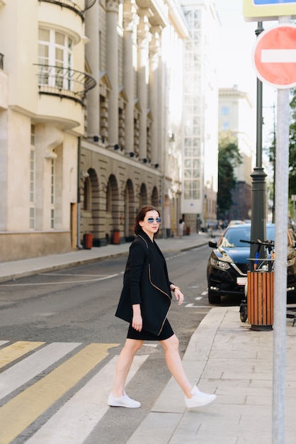 Schöne weiße Frau in einem schwarzen Kleid auf einem Hintergrund einer Stadtlandschaft