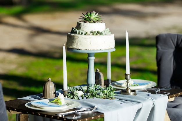 Schöne weiße Hochzeitstorte mit den Blumen im Freien