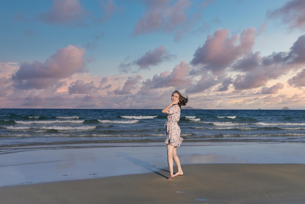 Schöne weißrussische Frau, die am Strand gegen einen dramatischen und romantischen Himmel spazieren geht