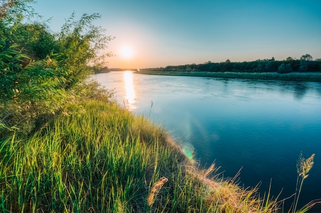 Schöne Wiese mit Fluss bei Sonnenuntergang