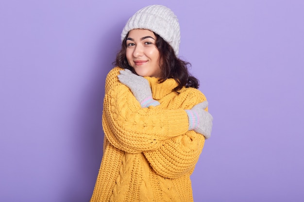 Schöne Winterfrau mit dunklem welligem Haar trägt gelben Pullover