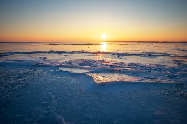 Schöne Winterlandschaft mit feurigem Himmel des Sonnenuntergangs und gefrorenem See. Zusammensetzung der Natur.