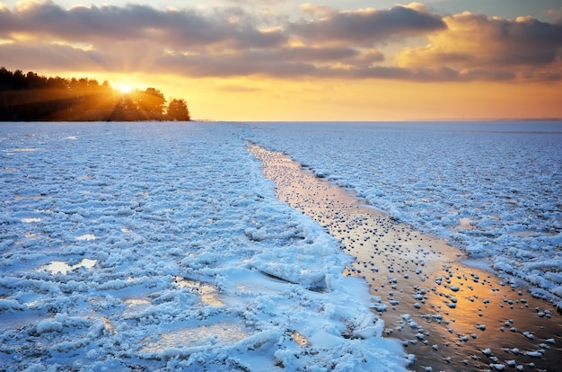 Schöne Winterlandschaft mit Sonnenunterganghimmel und zugefrorenem See