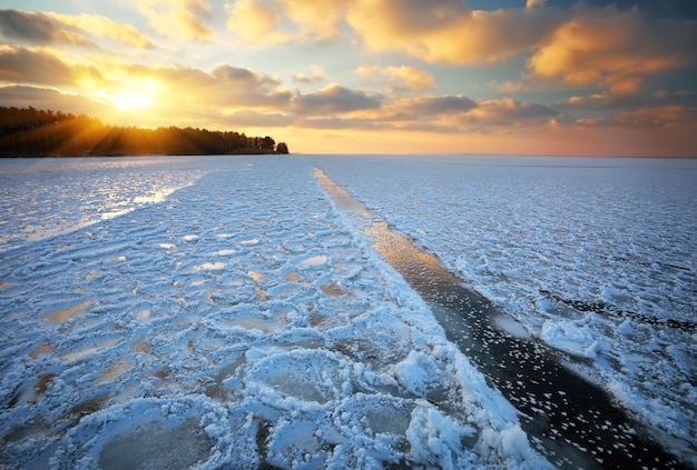 Schöne Winterlandschaft mit Sonnenunterganghimmel und zugefrorenem See