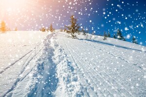 Schöne winterlandschaft. steiler berghang mit pfad und skipisten in weißem tiefschnee, grüne fichten, große schneeflocken und hell leuchtende sonnenstrahlen auf blauem himmel kopieren raumhintergrund.