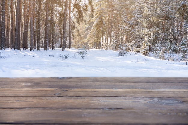 Schöne Winterszene. verschwommener Hintergrund des verschneiten Naturhintergrundes, Holztischplatte auf glänzendem Bokeh. Zur Produktpräsentation