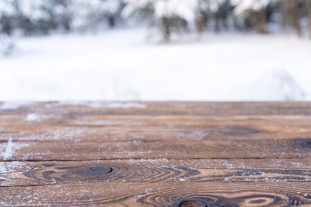 Schöne Winterszene. verschwommener Hintergrund des verschneiten Weihnachtsnaturhintergrundes, Holztischplatte auf glänzendem Bokeh. Für die Produktpräsentation Weihnachtsmock-up