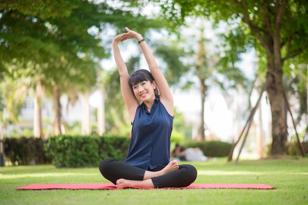 Schöne Yogafrau auf grünem Park