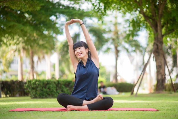 Schöne Yogafrau auf grünem Park