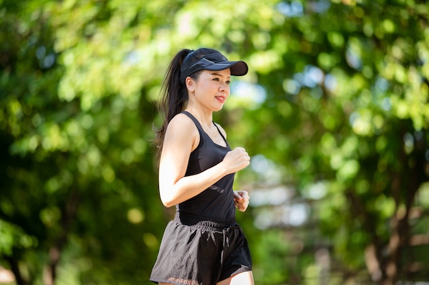 Schönen Sport asiatische Frau mittleren Alters im Freien spazieren im Park lächelnd, einen aktiven und gesunden Lebensstil zu leben.