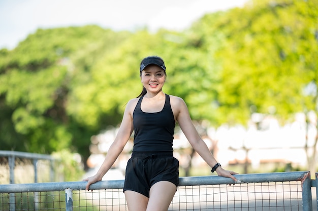 Schönen Sport asiatische Frau mittleren Alters im Freien spazieren im Park lächelnd, einen aktiven und gesunden Lebensstil zu leben.