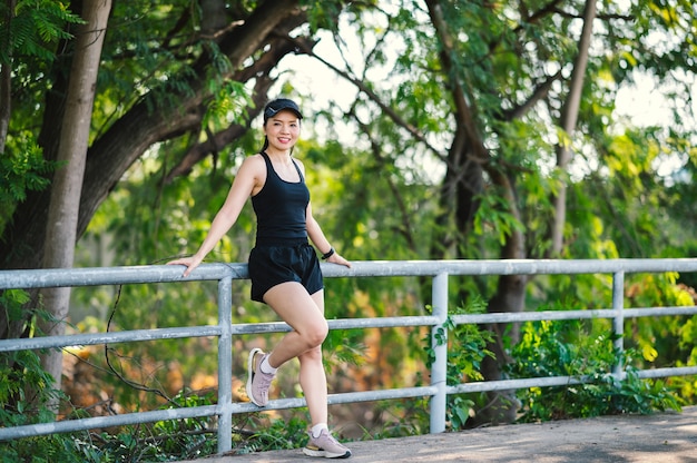 Schönen Sport asiatische Frau mittleren Alters im Freien spazieren im Park lächelnd, einen aktiven und gesunden Lebensstil zu leben.
