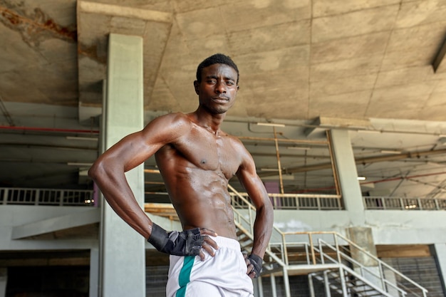 Schöner afroamerikanischer Sportler, der auf der Straße steht, während er nach dem Training eine Pause macht Schwarzer Mann, der sich nach dem Training ausruht