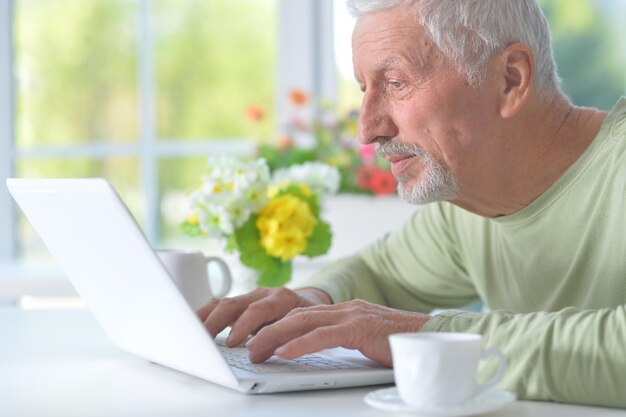 Schöner alter Mann mit einem Laptop