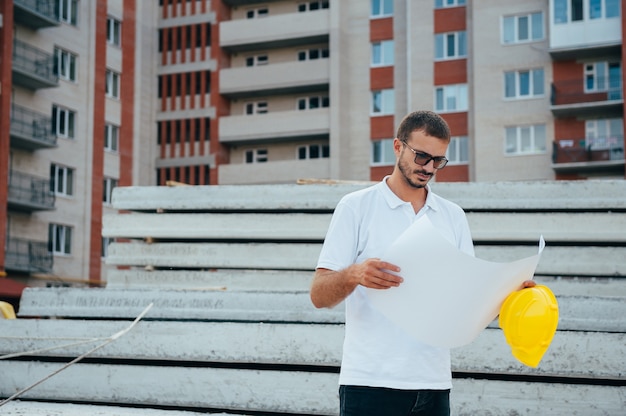 Schöner Architekt mit einem Helm auf der Baustelle