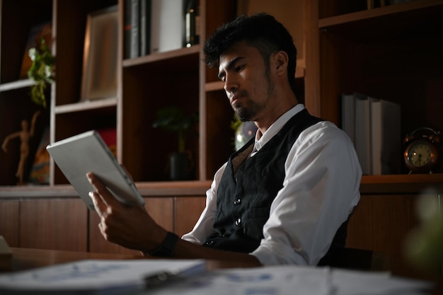 Schöner asiatischer Geschäftsmann oder männlicher Geschäftsführer mit digitalem Tablet