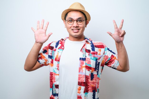 Schöner asiatischer Mann, der mit den Fingern nach oben zeigt und zeigt, während er selbstbewusst und glücklich lächelt