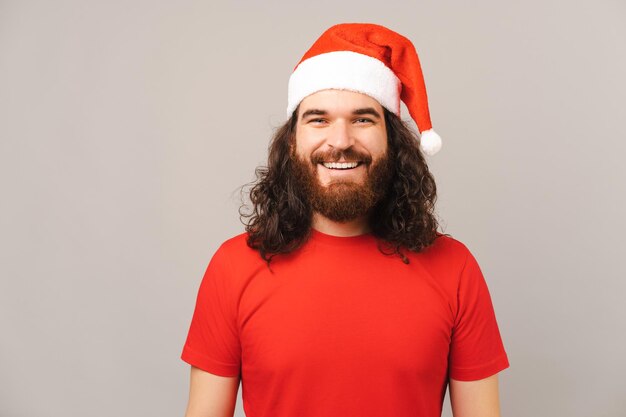 Schöner bärtiger Mann mit roter Weihnachtsmütze lächelt in die Kamera